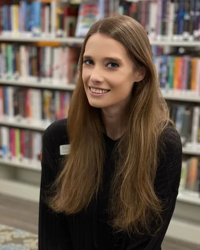 Vicki Karlovsky smiling in front of library shelves.