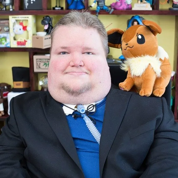 Steve Spohn in a suit in front of shelves of games and collectibles.